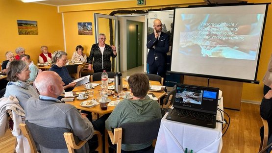 Rund 40 Teilnehmer sitzen bei einer Vorsorgeveranstaltung in der Seniorenpension "Ostseestrand", während Herr Schinschke und Frau Mehl die Vorsorgeveranstaltung begrüßen.