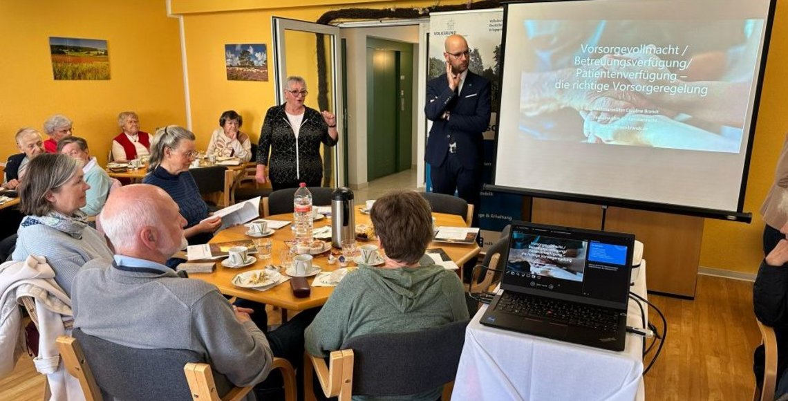 Rund 40 Teilnehmer sitzen bei einer Vorsorgeveranstaltung in der Seniorenpension "Ostseestrand", während Herr Schinschke und Frau Mehl die Vorsorgeveranstaltung begrüßen.